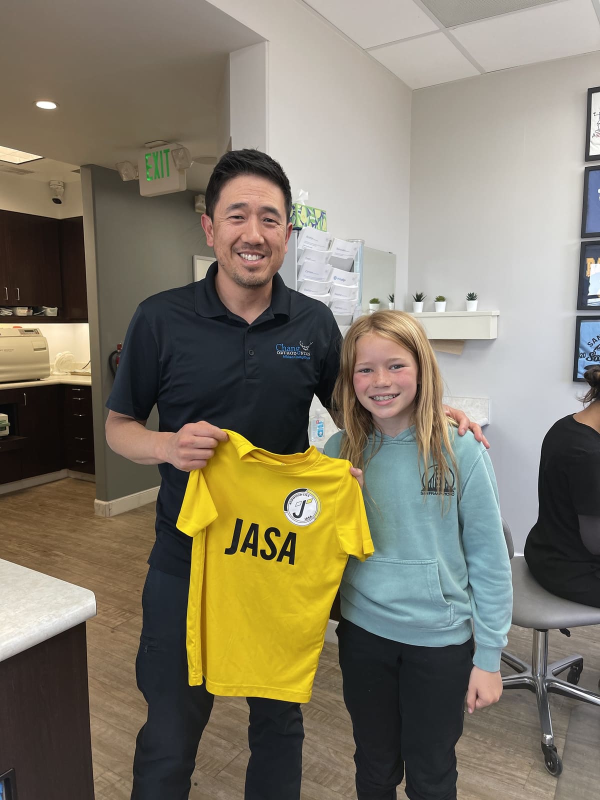 Dr. Chang with a young patient with braces holding her soccer jersey